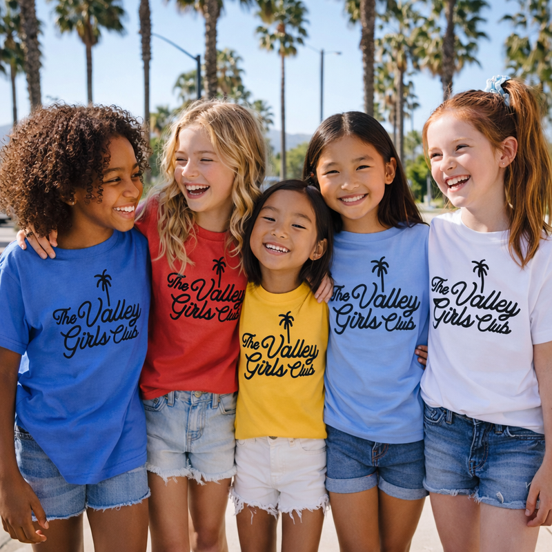 Five children wearing 'The Valley Girls Club' t-shirts in front of palm trees.